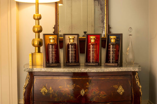 Four bottles from The Charles Gordon Collection sitting on a dresser between a lamp and a decanter.