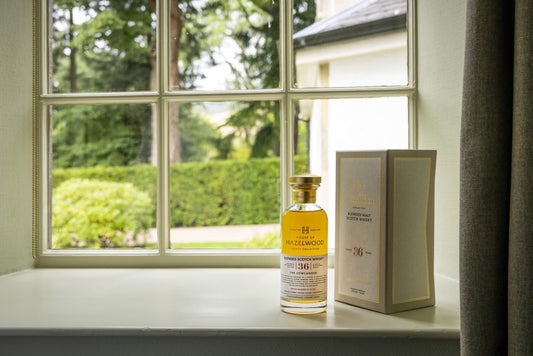 The Lowlander bottle sitting next to its box in front of a window.